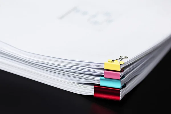 Pile or Stack of documents with colorful clips on black background.