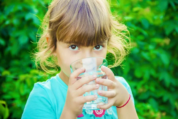 Çocuk bir bardak su elinde tutar..