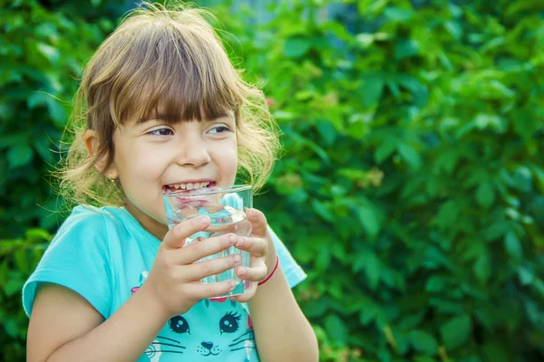 Çocuk bir bardak su elinde tutar..