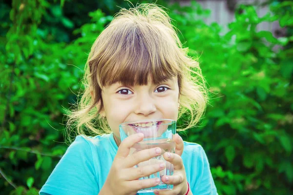 Çocuk bir bardak su elinde tutar..