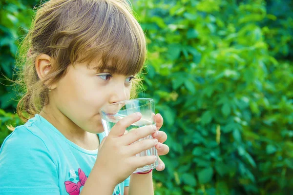 Çocuk bir bardak su elinde tutar..