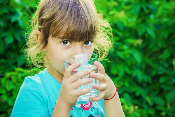Çocuk bir bardak su elinde tutar..