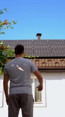 Adam evin çatısındaki güneş panellerine bakıyor. Seçici odaklanma. insanlar.