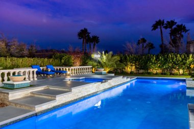 Yüksek Spa ve Ateş Kasesi Özellikleri ile Özel Tasarlanmış Yüzme Havuzu. Yükseltilmiş bir beton platformun içine yerleştirilmiş, basamaklı taş yığını olan Spa Kalkınma Duvarı