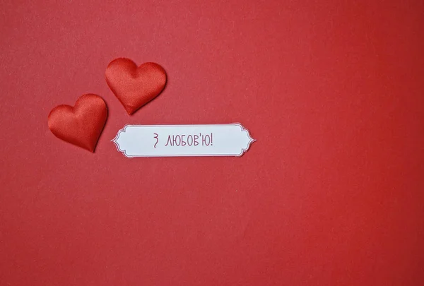 Two hearts and an inscription with love on a red paper background for Valentine\'s Day February 14th love