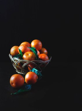 Siyah ahşap arka plan üzerinde bir sepet içinde Mandalina. Meyve sağlıklı gıda