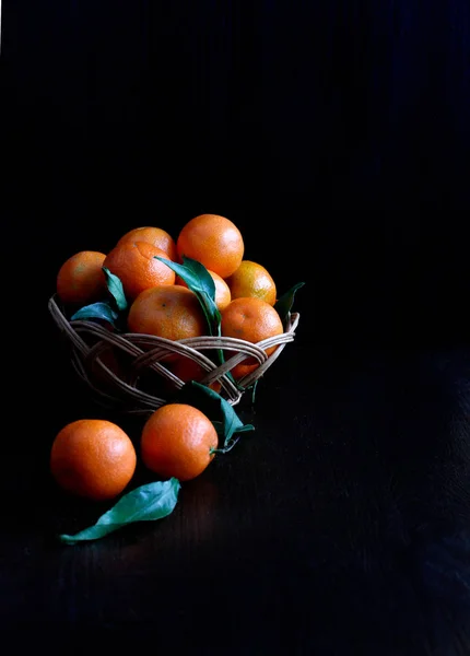 Tangerines in a basket on a black wooden background. Fruit healthy food