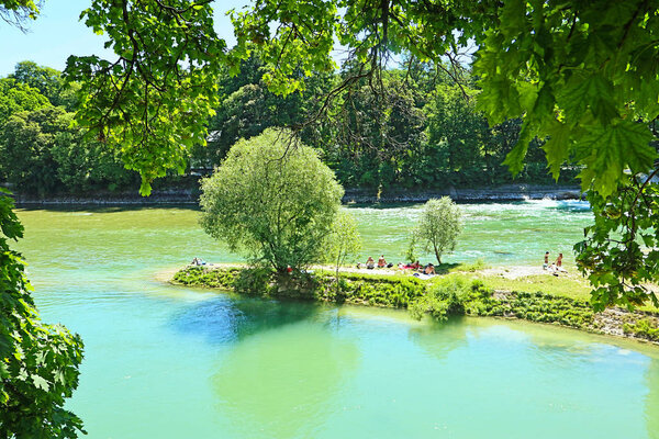 Munich, summer view of Isar river with people sun bathing on the the Praterinsel island 