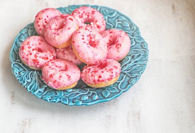 Pembe jöleli lezzetli mini çörekler ve mavi bir tabağa serpiştirilmiş şekerler.