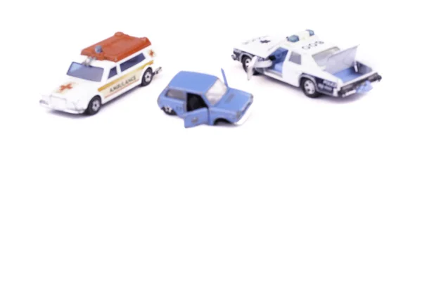 Blurred image smashed up and broken from accident or malfunction childrens toy car isolated on white background with ambulance and police on crash site helping concept of road safety and insurance — Stock Photo, Image