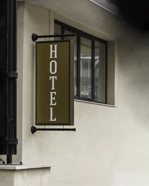 Vertical hotel sign text on billboard outdoor mock up neon sign informing passing people tourist pedestrian or car drivers attached to the wall of hotel building next to entrance background