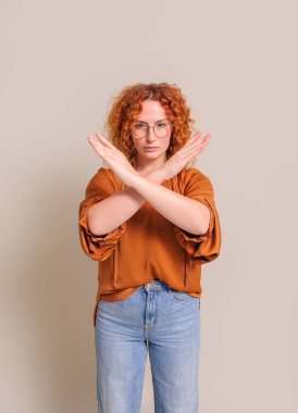 Kendine güvenen genç bir kadının portresi beyaz arka planda çapraz ellerle reddedilme işareti gösteriyor.