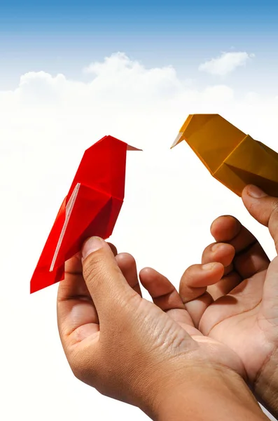 Elinde iki Origami kağıt kuşu tutan adam. İş ve motivasyon için kavramsal bir fikir. Gökyüzü sınırdır.. 