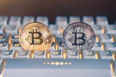 Sarı ışık ya da RGB klavyesi ve turuncu ışık fişeği olan beyaz bir klavyede altın bitcoin ve gümüş bitcoin şifreli sanal para. Engelleme teknolojisi kavramı.