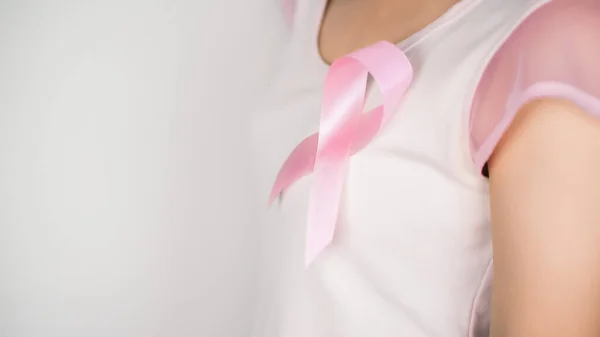 Pink ribbon on the left chest of Woman wearing a white t-shirt with white background, Breast cancer symbol, Breast cancer awareness month. Important days in October