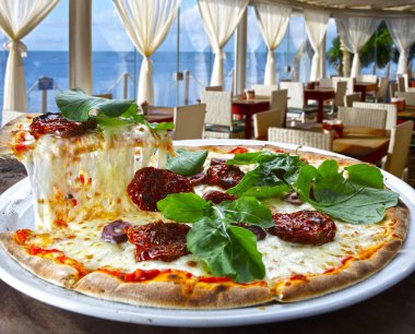 Kurutulmuş domates, rucula ve mozzarella içinde deniz manzaralı pizzacı pizza