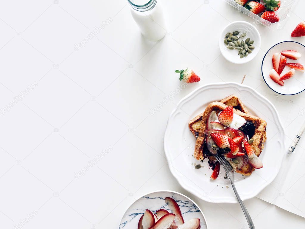 Healthy breakfast with french toasts, strawberries, rose apple and pumpkin seeds, top view on a white background, copy space