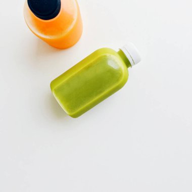 Taze ve sağlıklı avokado ve portakal suyu üzerinde beyaz bir arka plan kopya alanı ile üstten görünüm izole şişelerde