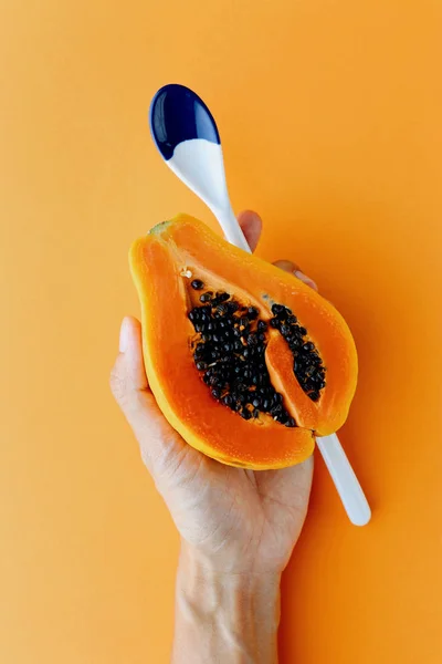 Kezében Fél Hawaii Papaya Kanállal Narancssárga Háttérrel Élelmiszer Koncepció Felülnézet — Stock Fotó