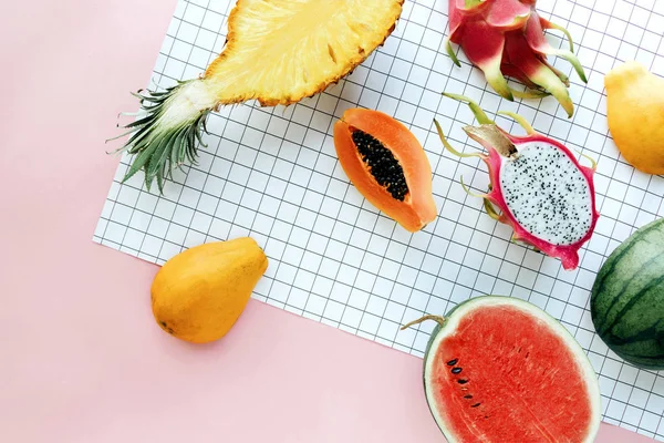 Bir beyaz kılavuz ve pastel pembe arka plan düz yatıyordu tropikal yaz meyve. Ananas, karpuz, Hawaii papaya, dragon meyve ile yaratıcı yiyecekler kavramı