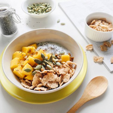 Sağlıklı kahvaltı kaseyle chia tohum puding, mango, tahıl, kabak çekirdeği ve ayçiçeği tohumu bir mutfak masasında