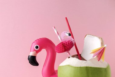 Bir pastel pembe flamingo şişme içki sahibi, yaz vibes kavramı ile taze Hindistan cevizi