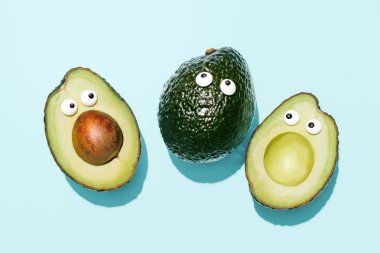 Komik suratlar avokado bir pastel mavi arka plan, yaratıcı sağlıklı gıda kavramı, kırpma yolu ile üstten görünüm