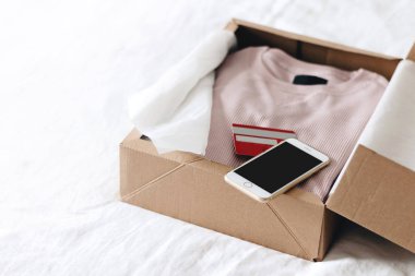 Online alışveriş moda öğeleri üzerinde beyaz bir arka plan kopya alanı ile smartphone ve kredi kartı kullanarak kutusunu açma
