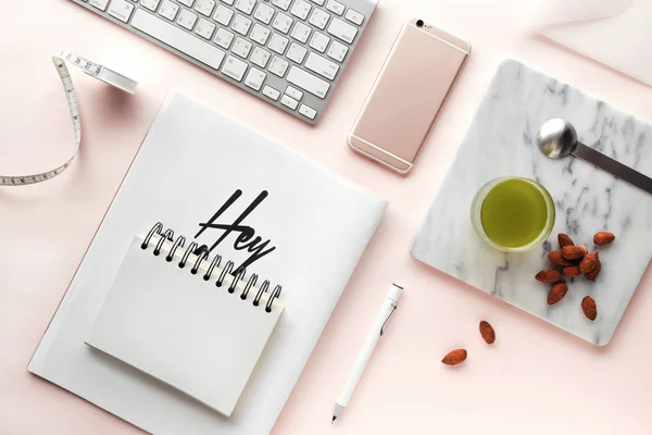 Yaratıcı düz çalışma alanı en az tarzı ile yatıyordu. Bilgisayar, smartphone, dergi, defter, kalem, tapeline, badem ve bir bardak yeşil çay pastel pembe arka plan, üstten görünüm üzerinde modern resepsiyon