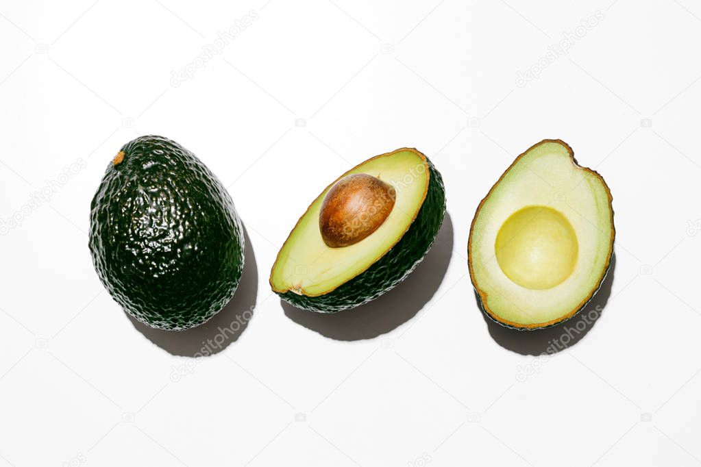 Fresh organic hass avocados on a white background, creative flat lay healthy food concept