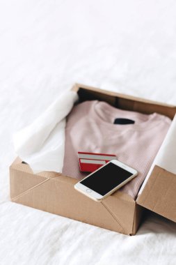 Online alışveriş moda öğeleri üzerinde beyaz bir arka plan kopya alanı ile smartphone ve kredi kartı kullanarak kutusunu açma