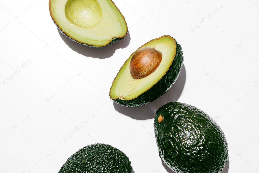 Fresh organic hass avocados on a white background, creative flat lay healthy food concept