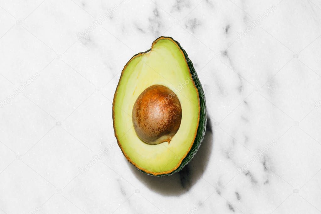 Fresh organic hass avocados on a white marble background, creative flat lay healthy food concept