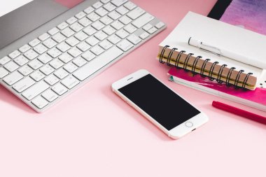 Modern resepsiyon ile smartphone, bilgisayar; Defter ve kalem pastel pembe arka plan, yaratıcı kavramı çalışma alanıyla kopya alanı üzerinde