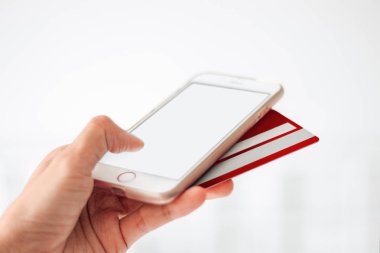Kopya alanı, online alışveriş kavramı ile beyaz bir arka plan üzerinde kutusunu açma moda öğelerle smartphone ve kırmızı kredi kartı tutan el mockup görüntü
