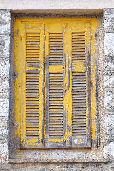 石垣の上の古い木製窓黄色シャッター — ストック写真