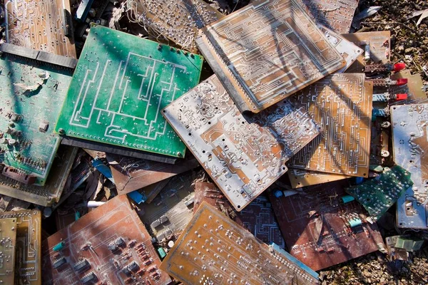 Old, used and broken electronic circuit chips lie on ground in the sun, background texture photo