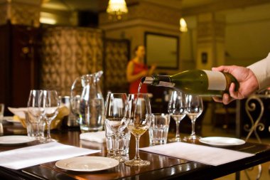 şarap bir restoranda test sırasında bir sommelier kadın açıklar iken garsonun el Beyaz şarap kadehinin dökülen.
