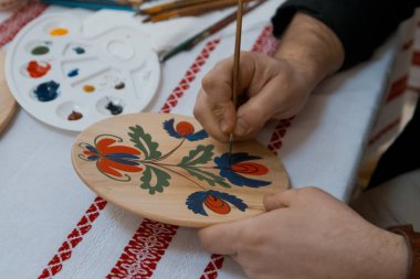 handpainting el yapımı dekoratif ahşap yuvarlak plaka üzerinde elini bir parlak çiçek desenli bir fırça, Petrykivka resim stili ile boyar.