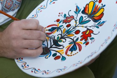 Kiev, Ukrayna - 17.11.2017: handpainting el yapımı dekoratif seramik plaka üzerinde Usta'nın el bir fırça, Petrykivka resim stili, etnografik ana sınıfı, etnografik Festivali parlak çiçek desenle boyar
