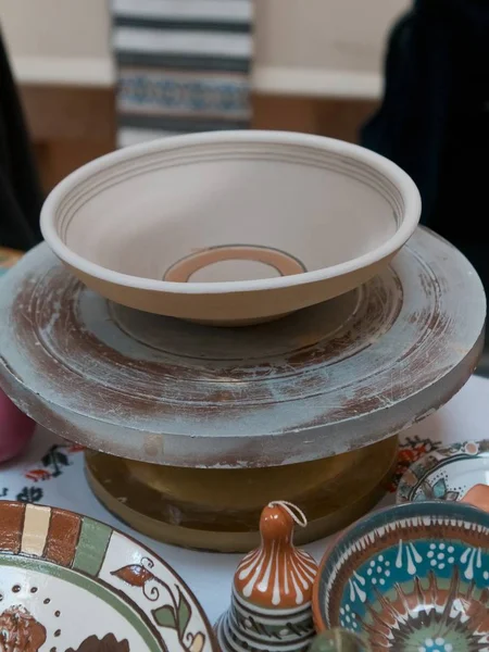 handmade clay plate on a mobile pottery wheel ready for painting with retro folk ornaments