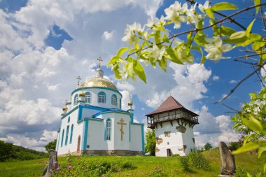 Busha, Ukrayna - 09.06. 2019: Devlet tarihi kültür parkında modern Rus Ortodoks Kilisesi ve antik kozak kulesi, önünde beyaz çiçeklerle bulanık açan yasemin dalı, inanç ve barış kavramı