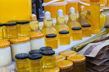 bright clear yellow honey in different shape bottles and jars sold at a fair, fresh ecological summer seasonal product from a farmer's apiary