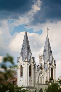 Bar, Ukrayna - 11.06.2019: Hıristiyan tapınağının kuleleri ve çatısı, Aziz Anna Roma Katolik Kilisesi gökyüzündeki yoğun yağmurlu bulutlara karşı yumuşak gün ışığında, antik mimari başyapıt ve popüler turizm simgesi