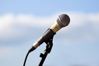 Vinnytsia, Ukrayna - 15.08.2014: Mavi gökyüzüne karşı parlayan mikrofon başı ve kablo, rock müzik konserinden önce kullanılan ve giyilen ekipmanlar, bulanık arkaplan