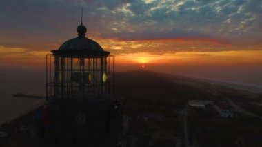 Sahile güneş doğarken bir dron 4 k tarafından görüldüğü gibi bir deniz feneri ile