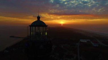 Sahile güneş doğarken bir dron 4 k tarafından görüldüğü gibi bir deniz feneri ile