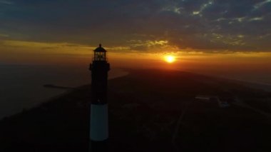 Sahile güneş doğarken bir dron 4 k tarafından görüldüğü gibi bir deniz feneri ile