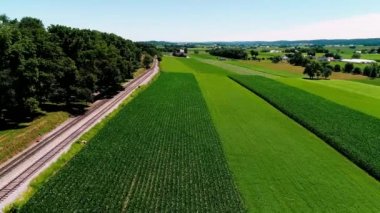 Tren geçerken Amish çiftlik arazileri ve kırsal yoluyla bir geç günbatımı yaz gününde dron tarafından görüldüğü gibi Buhar