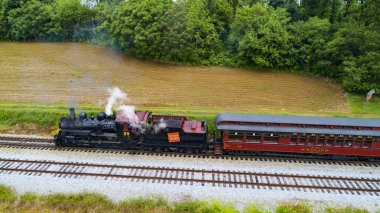Ariel görünümünü bir Buhar yolcu treni çekerek piknik alanı üfleme duman içine yaz bir dron tarafından görüldüğü gibi güneşli bir